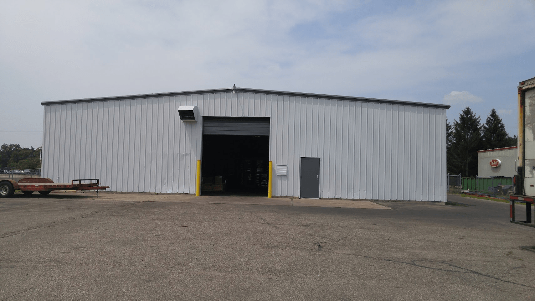A large white building with a trailer parked in front of it.