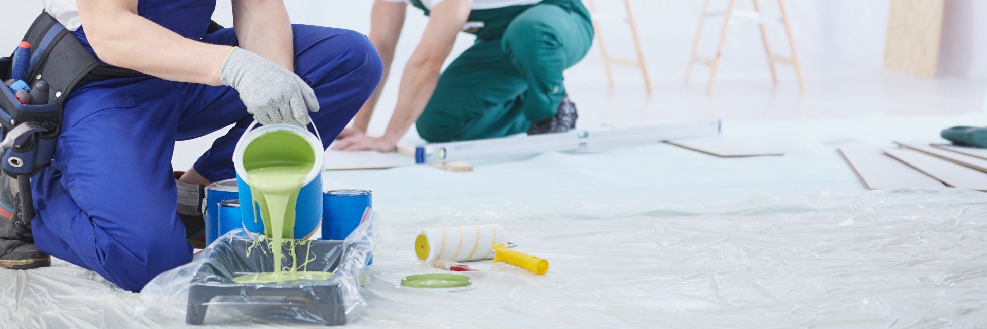 A man is pouring green paint into a tray.