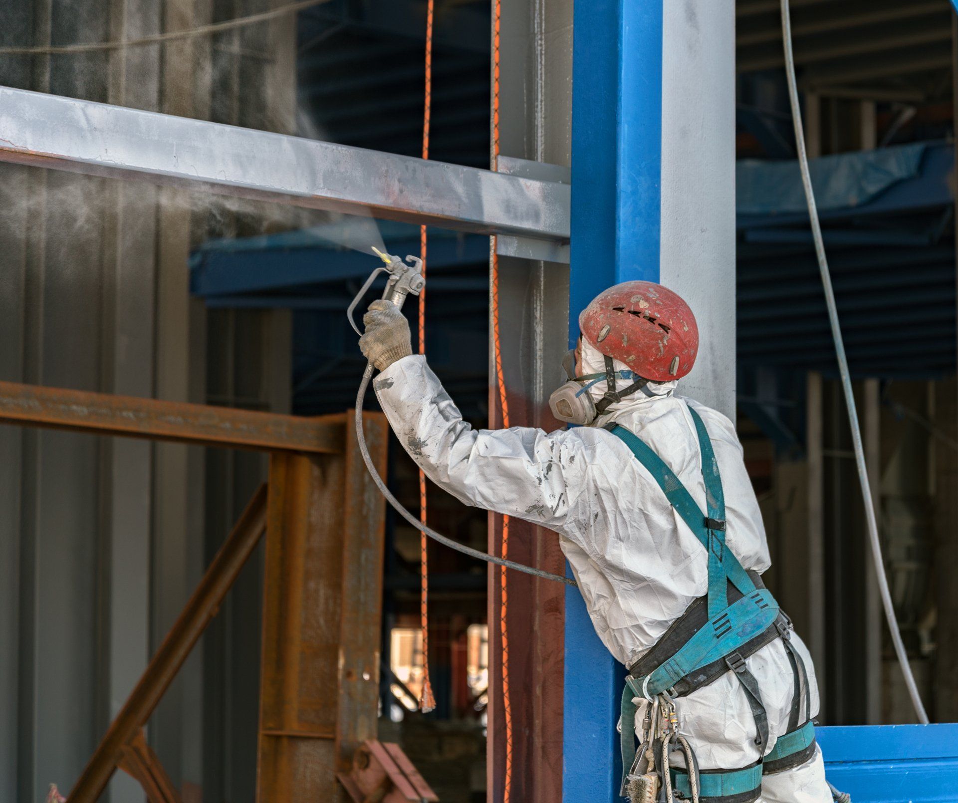A man in a gas mask is spray painting a building.