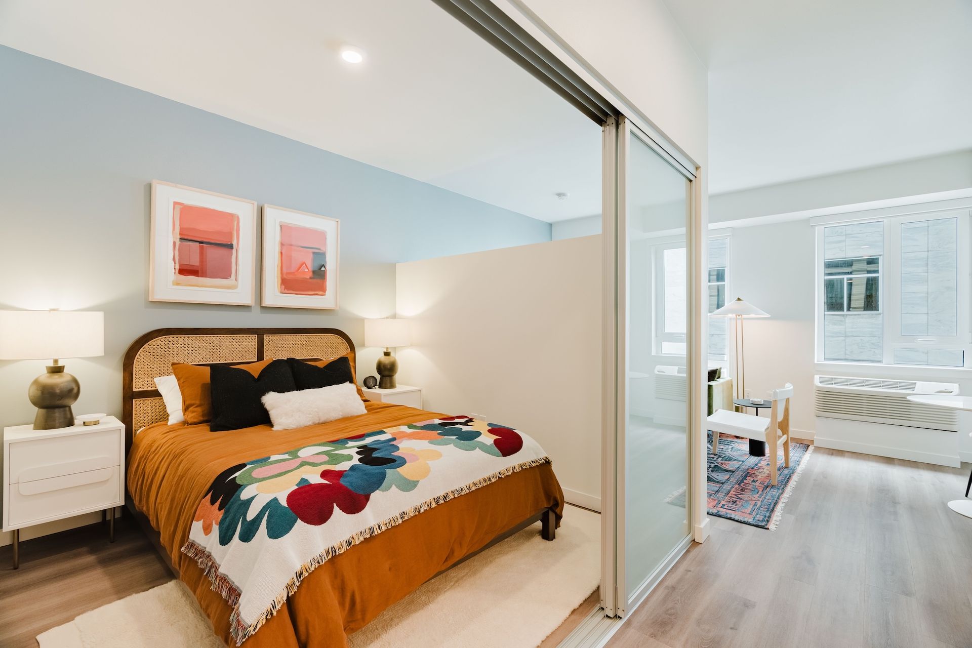 A bedroom with a large bed and a sliding glass door between the bedroom and the bathroom.