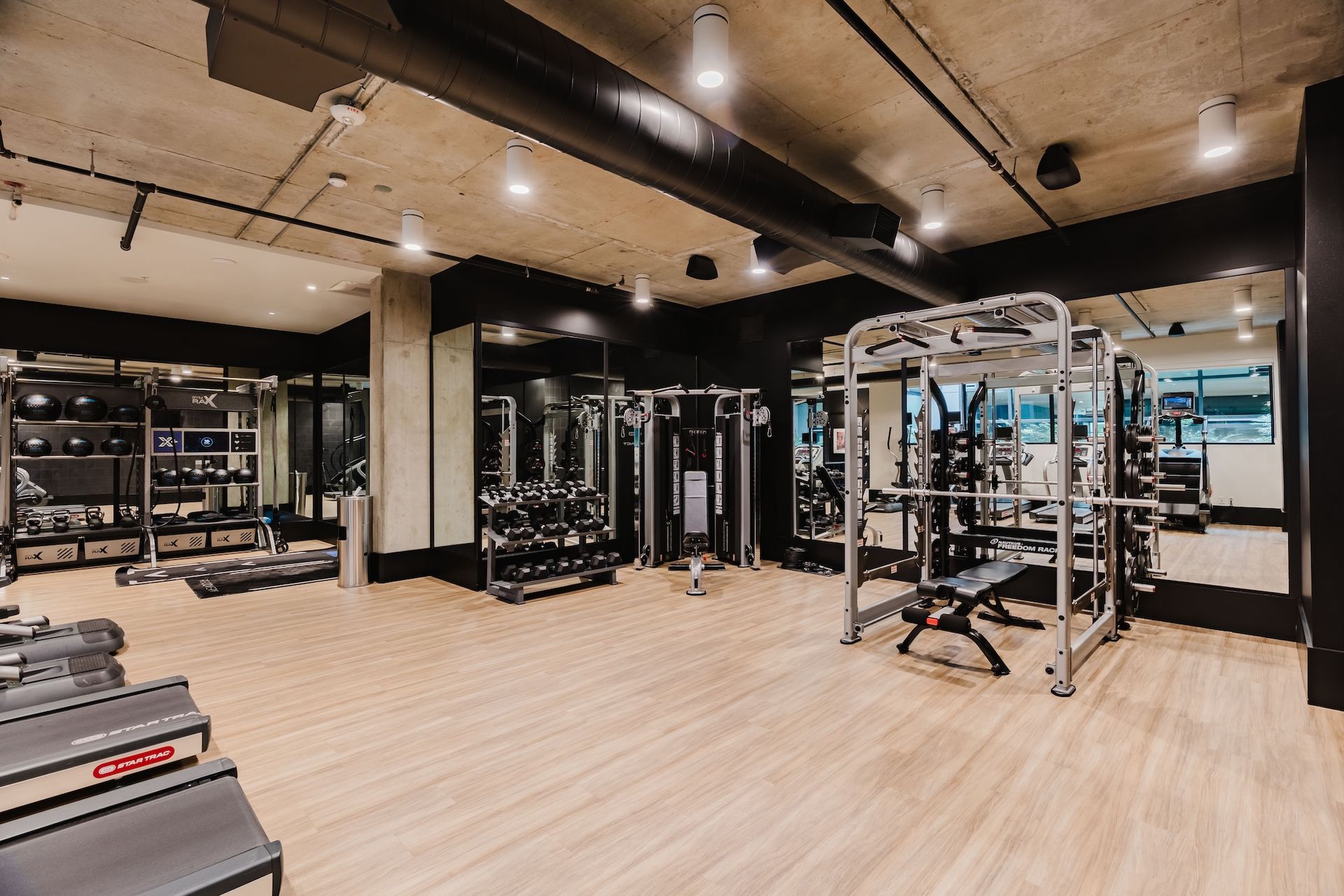A large gym with a lot of equipment and mirrors.