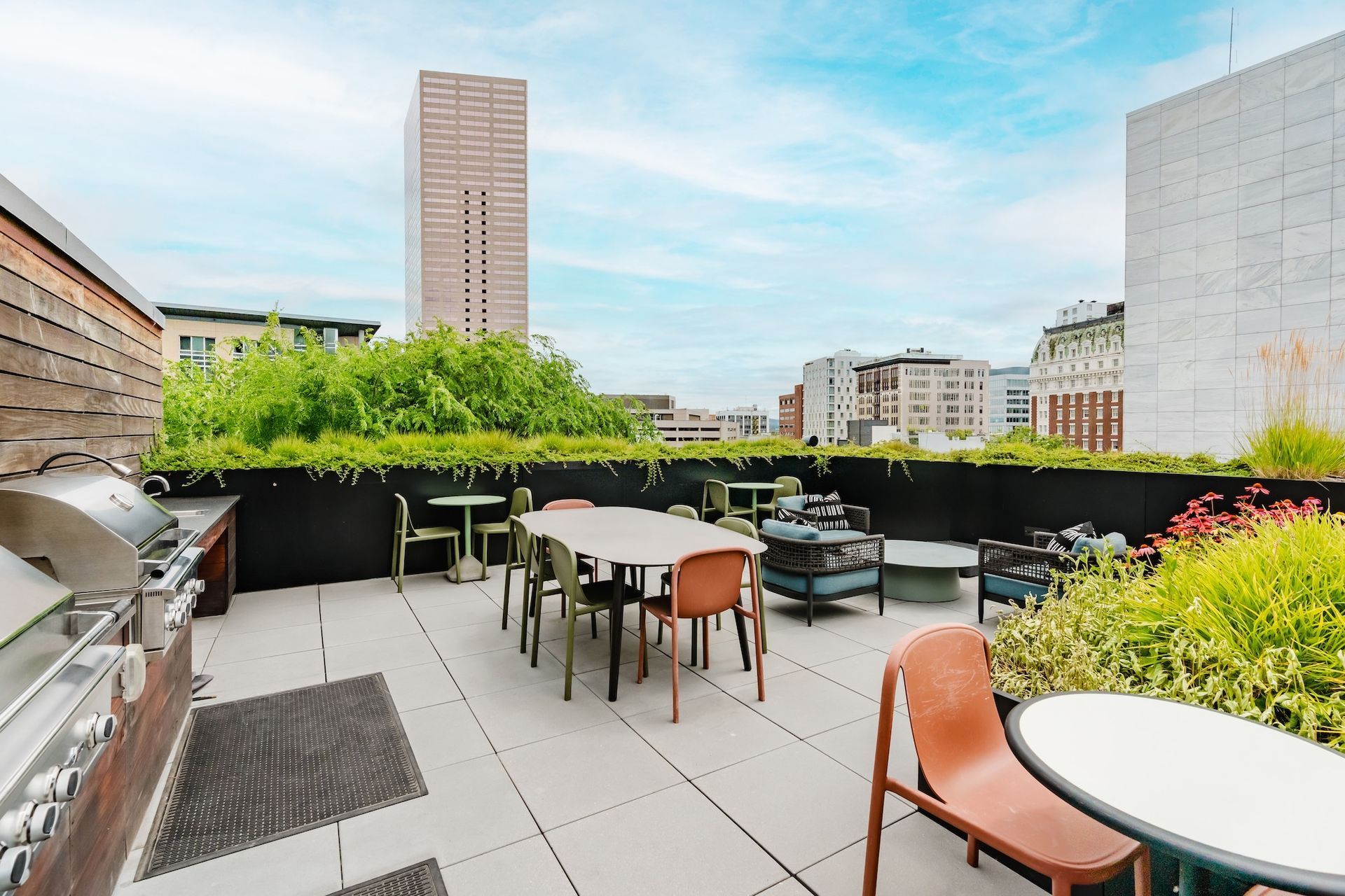 A rooftop patio with tables and chairs and a grill