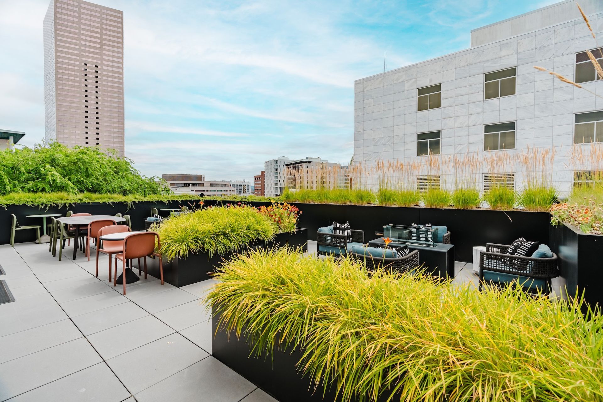 A rooftop garden with tables and chairs and a building in the background