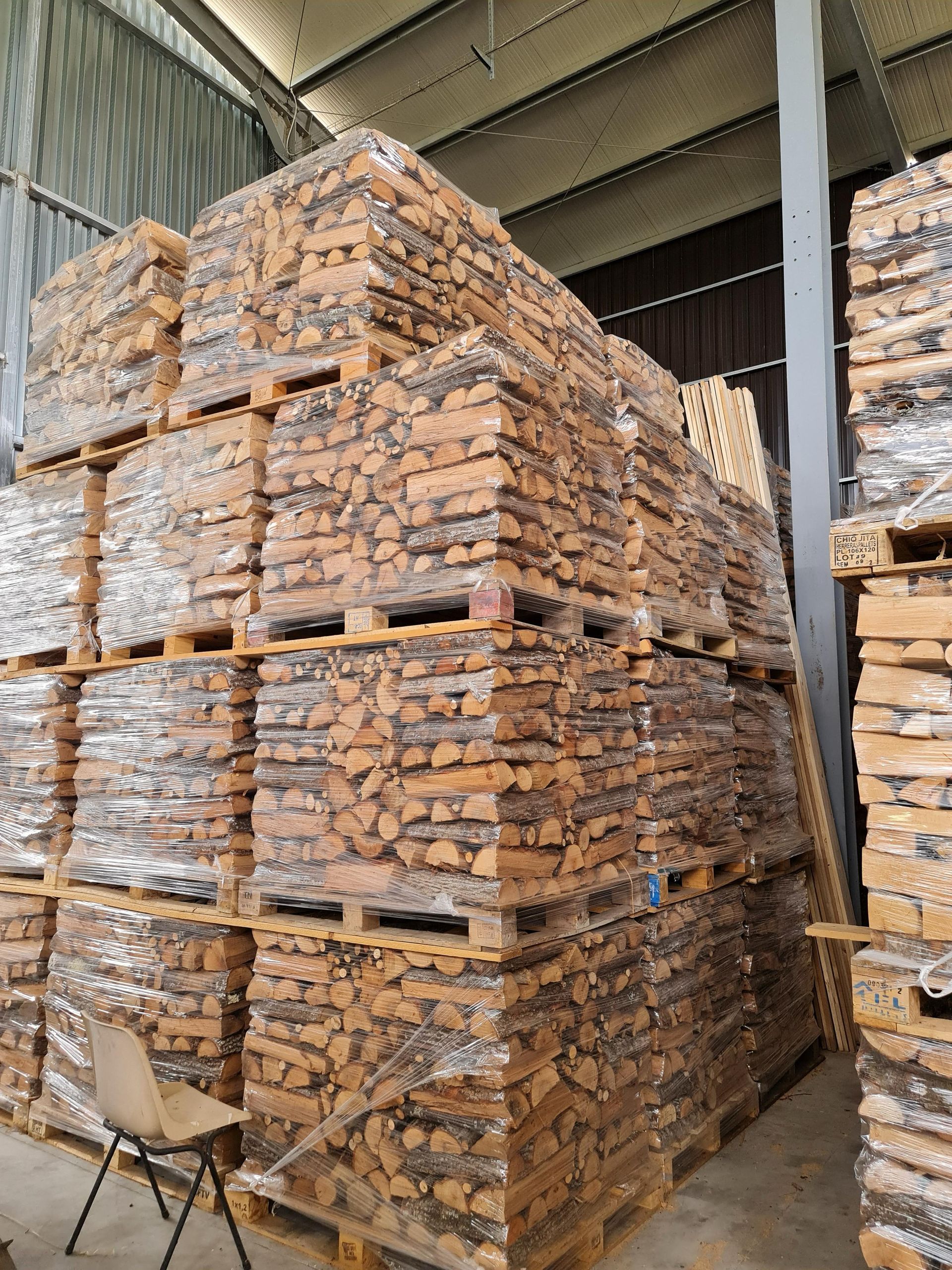 Una grande catasta di legna è accatastata l'una sull'altra in un magazzino.