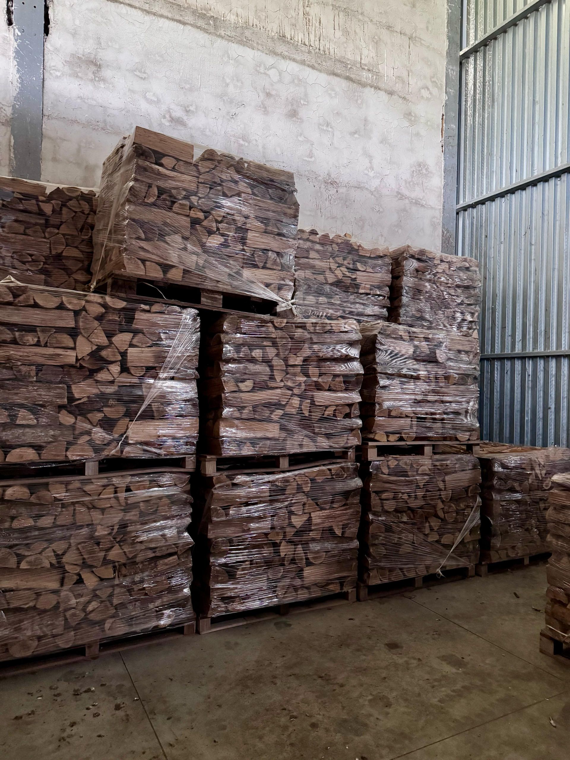 Un magazzino pieno di pallet di legno accatastati uno sopra l'altro.