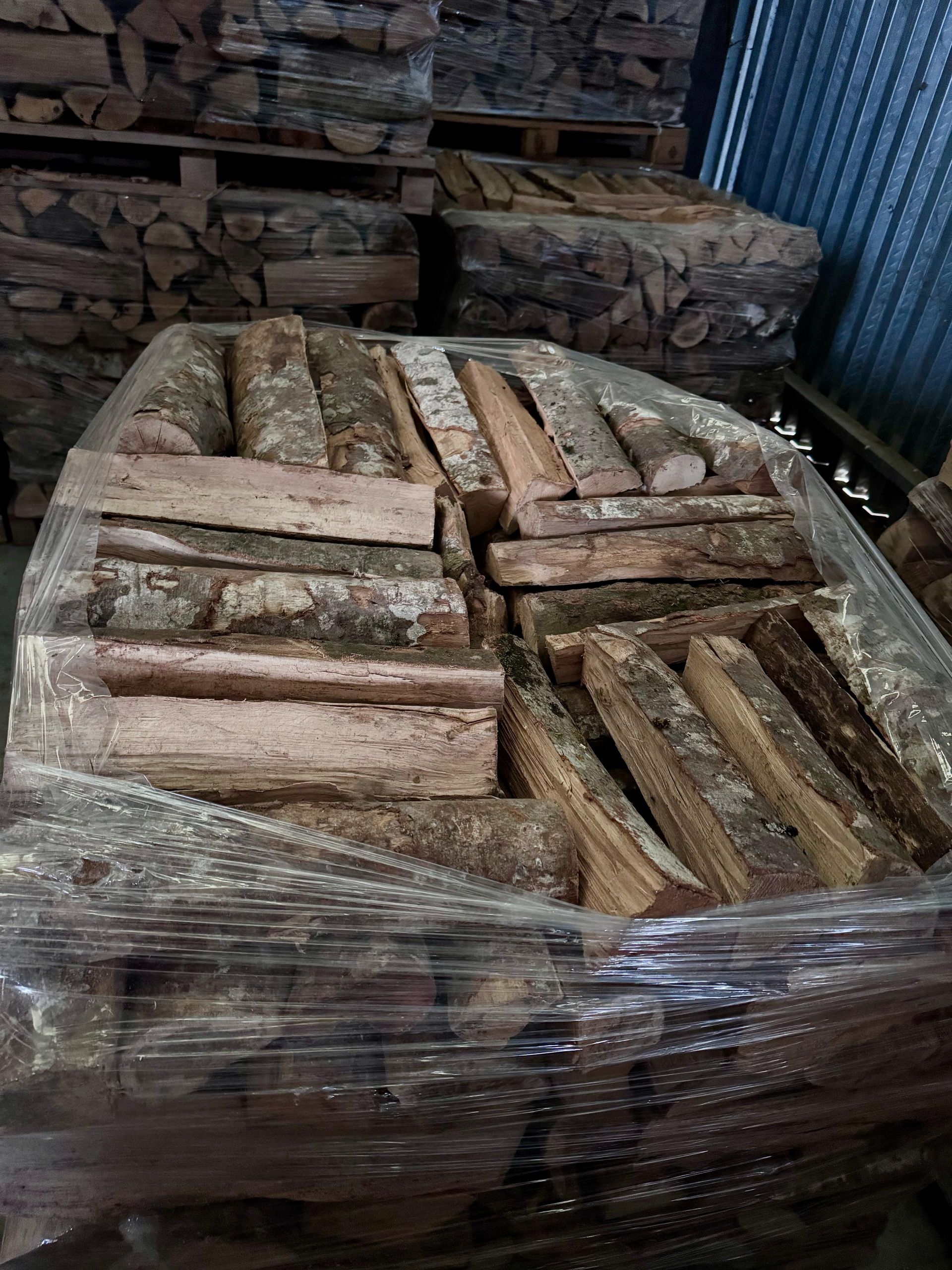 Una pila di tronchi avvolti nella plastica in un magazzino.