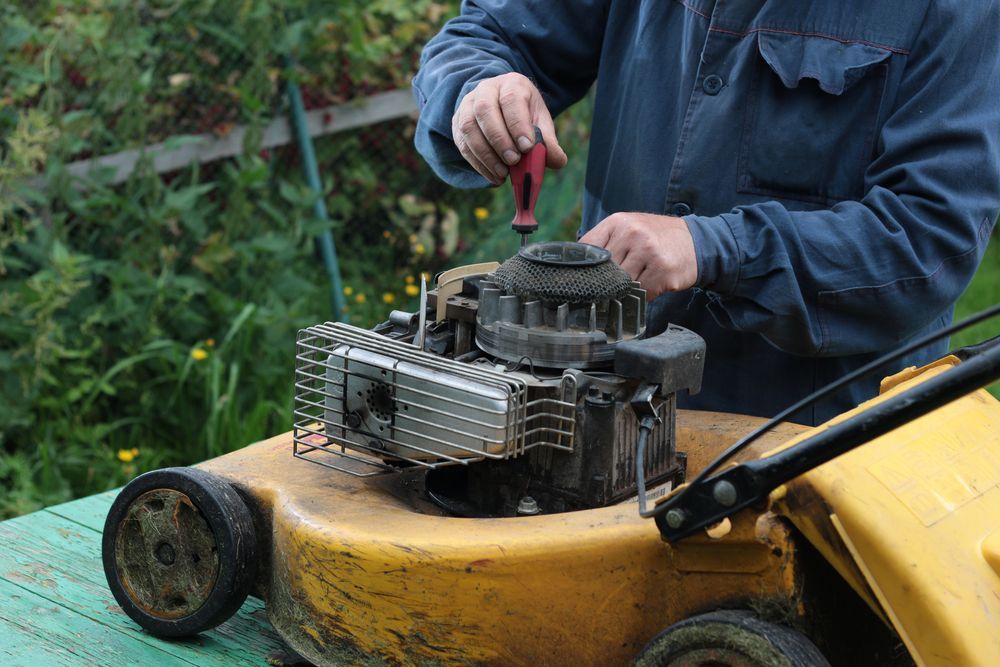 A Man Is Repairing A Lawn Mower — Plateau Mower Repairs In Alstonville, NSW