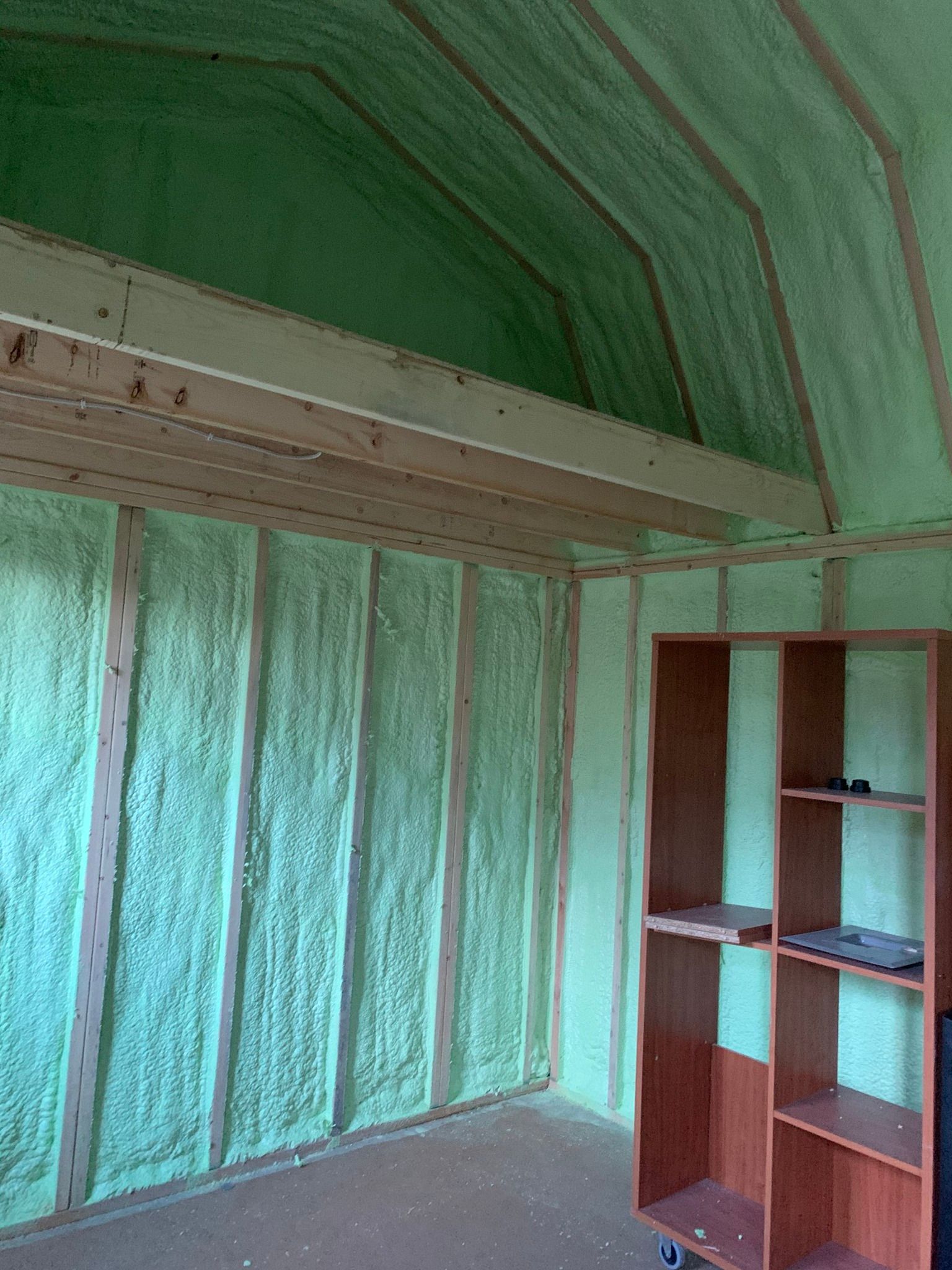 a room with green foam insulation and wooden shelves .