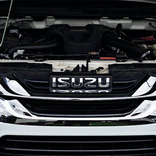 Close-up of an Isuzu truck front grille with chrome lettering and open hood