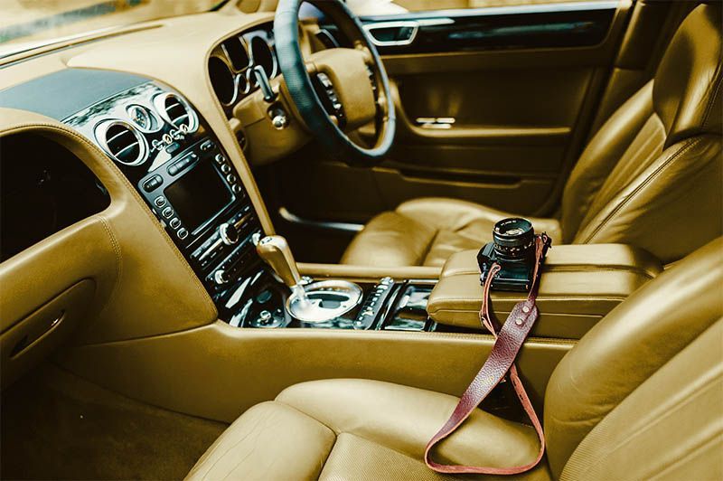 Luxury tan leather car interior with center console and a pink strap on the passenger seat