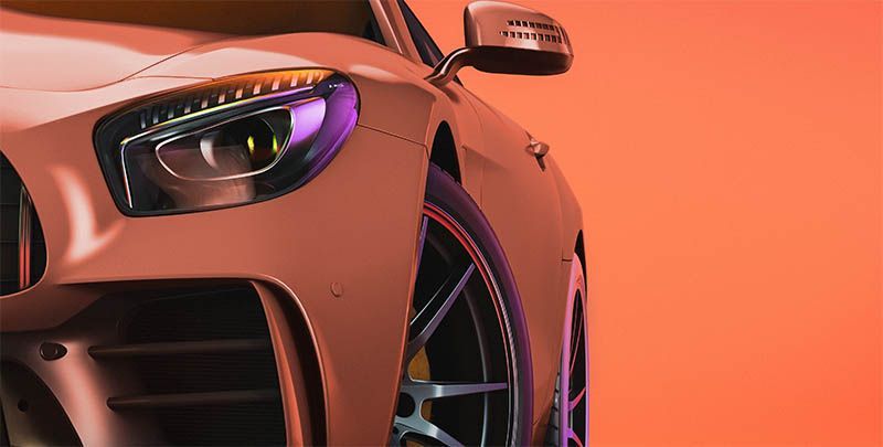 Close-up of a car front with a glowing headlight and alloy wheel against an orange background