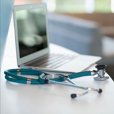 Uno stetoscopio è appoggiato su un tavolo accanto a un computer portatile