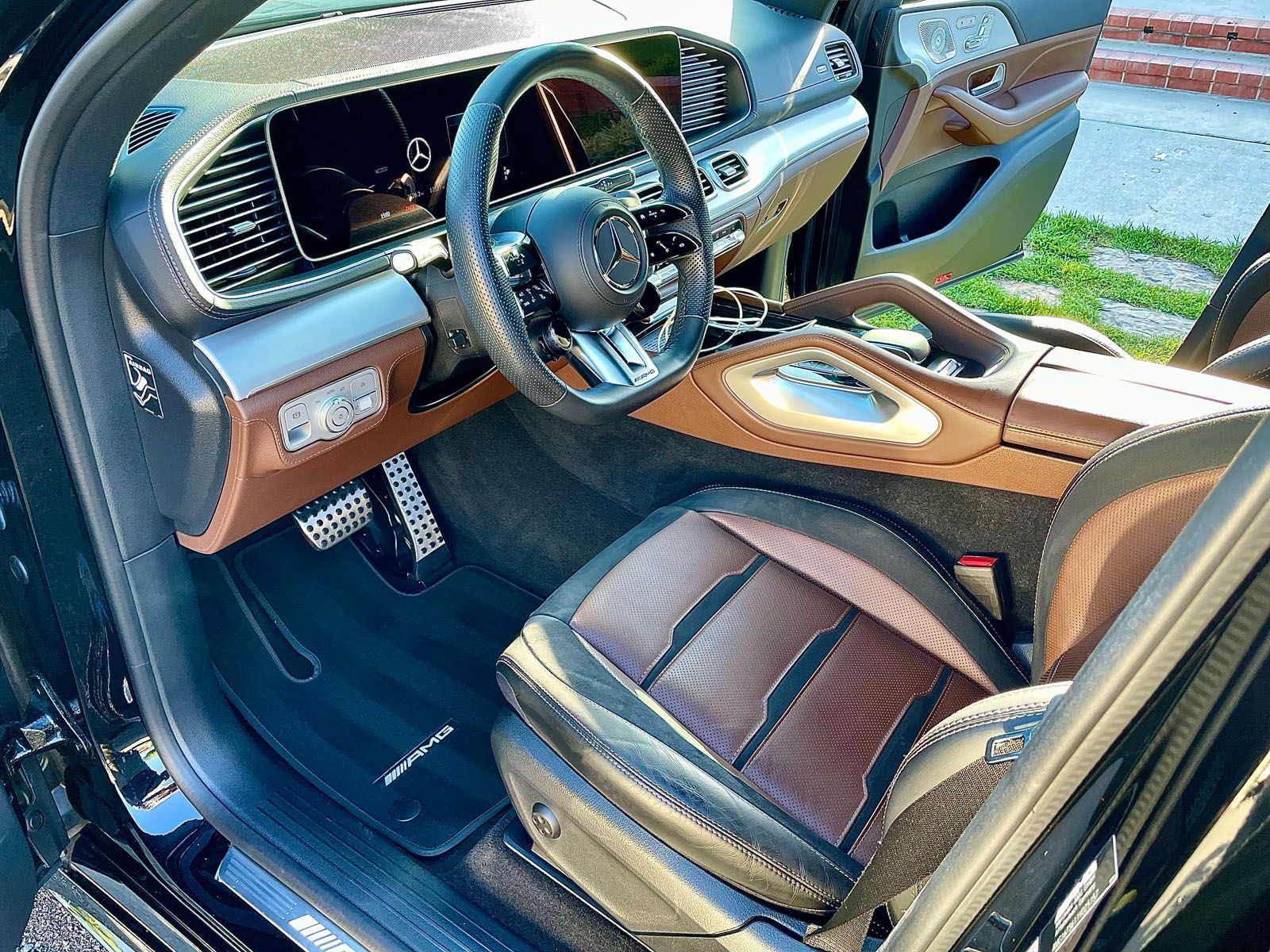 Luxury car interior with tan leather seats and a black carbon fiber console.