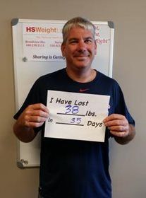 A man is holding a sign that says `` i have lost 38 lbs in 35 days ''.