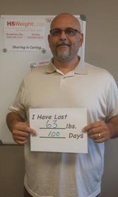 A man is holding a sign that says `` i have lost 63 lbs . 100 days ''.