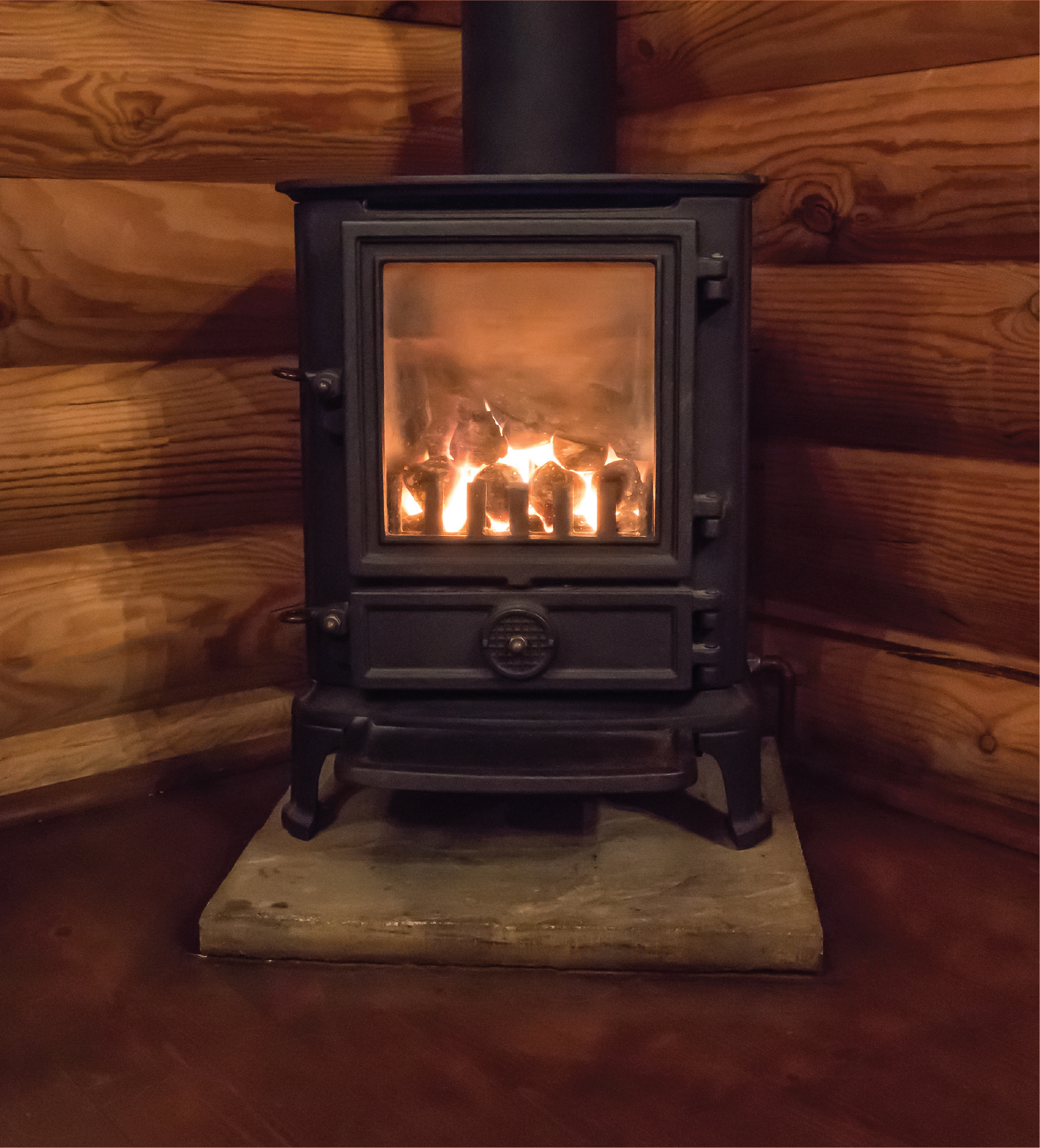 A wood stove is lit up in a log cabin