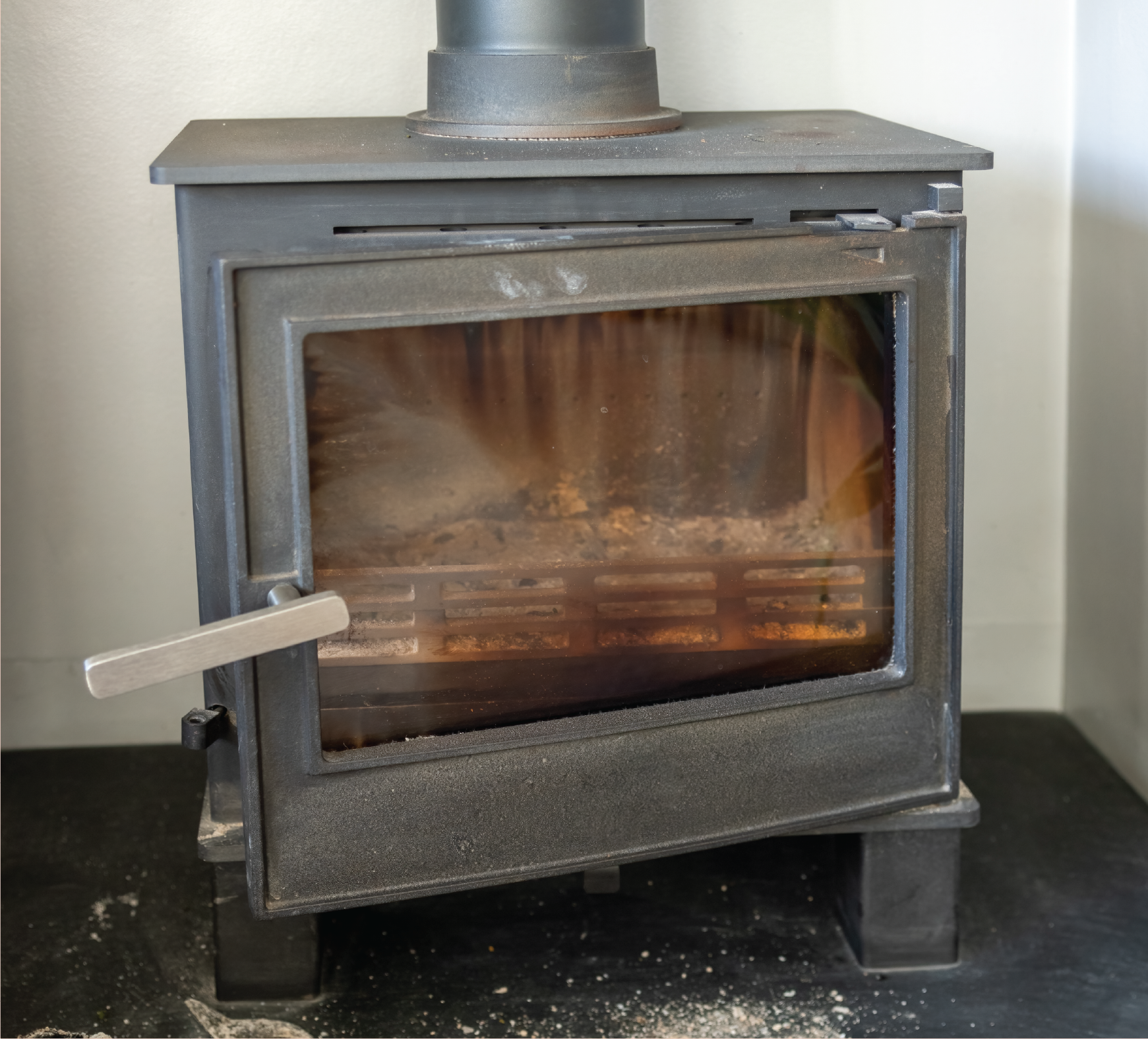 A wood stove with the door open and smoke coming out of it