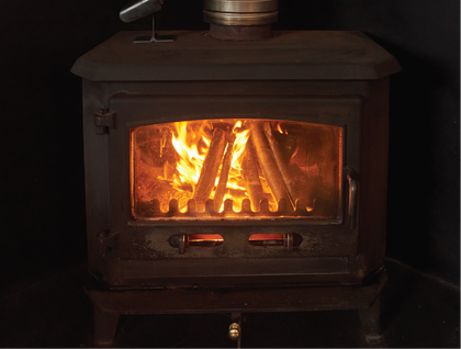 A wood stove is lit up in a dark room