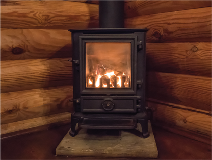 A wood stove is sitting in a fireplace next to a metal bucket.