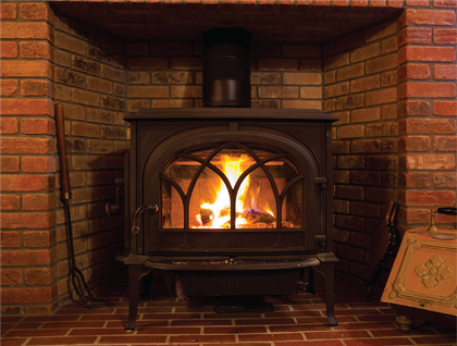 A wood stove is sitting in a fireplace in a room.