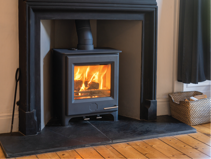 A wood stove is sitting in a fireplace in a living room.