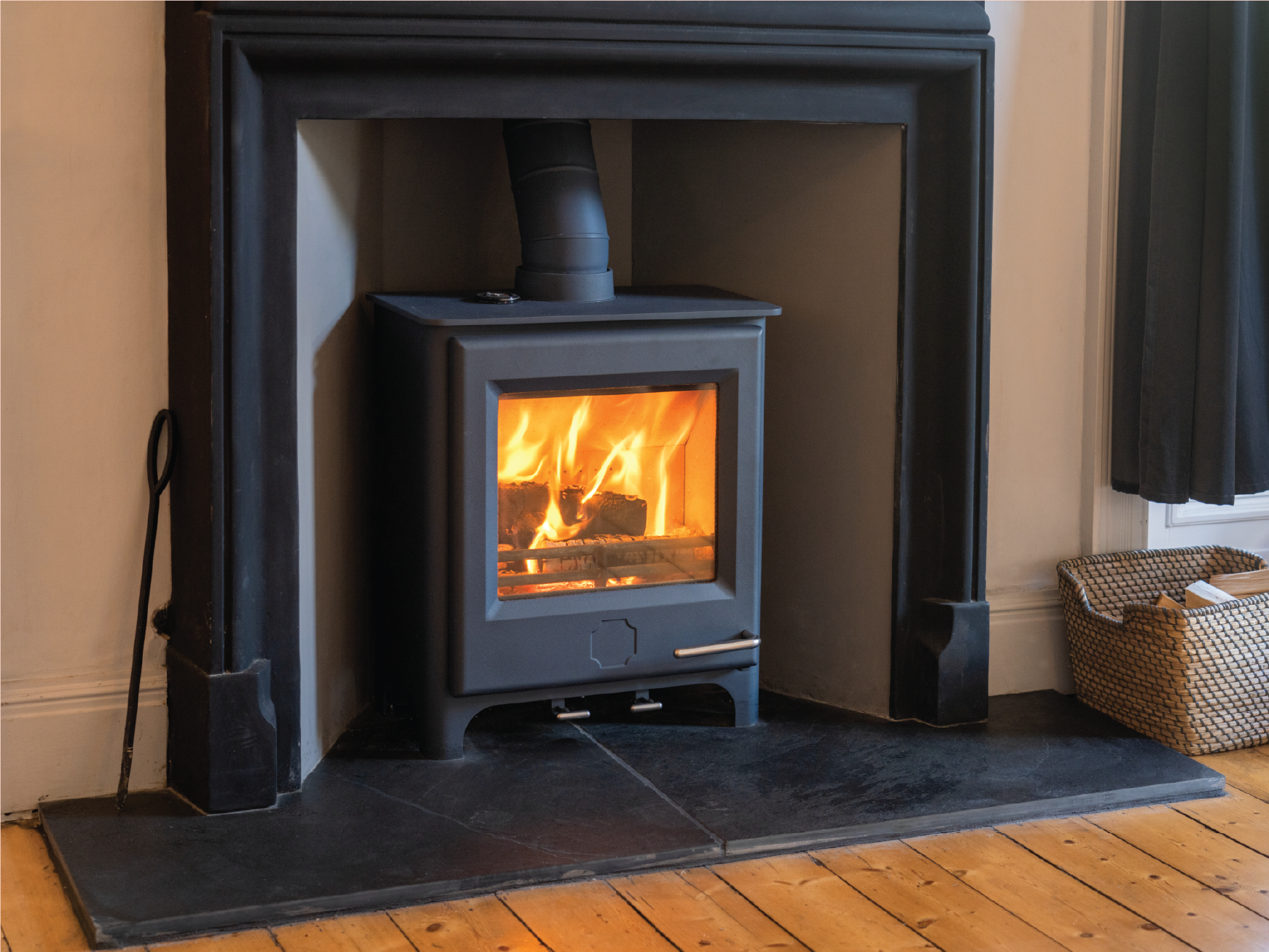 A wood stove is sitting in a fireplace in a living room.