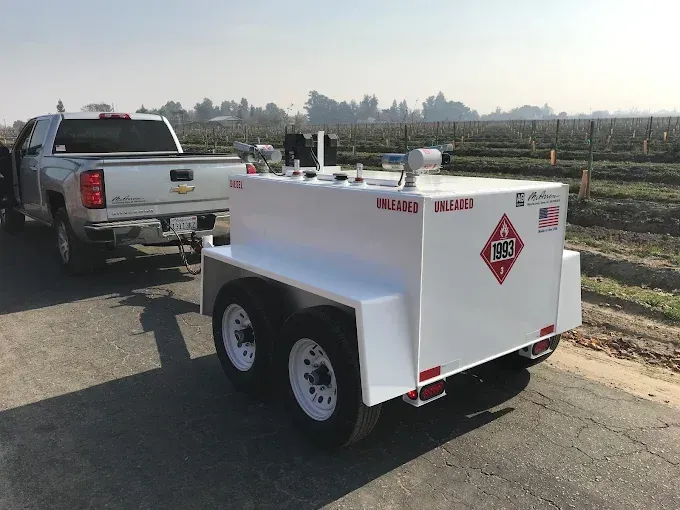 White utility trailer parked behind a silver pickup truck on a rural roadside.