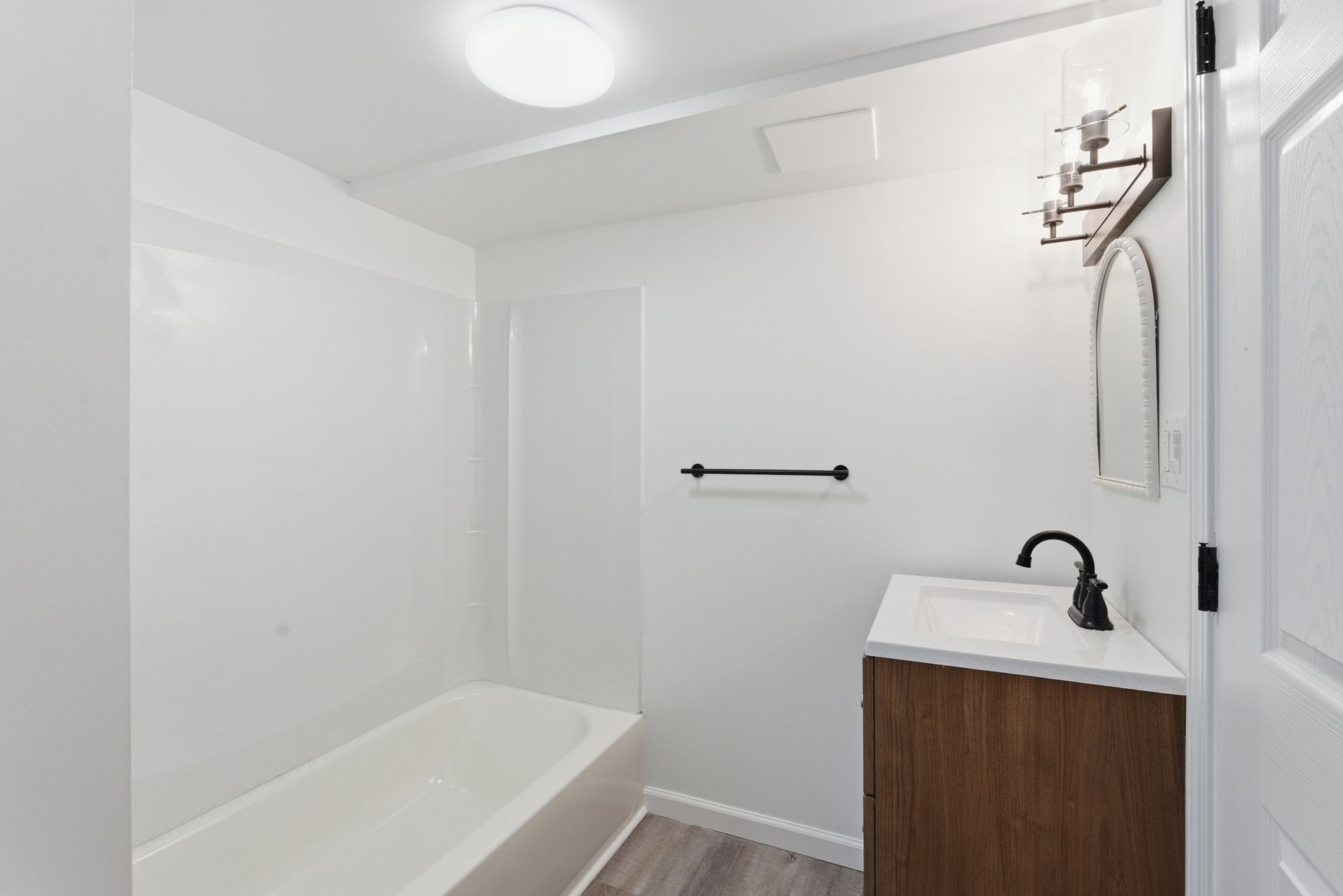 Bright white bathroom with tub, vanity sink, and towel bar