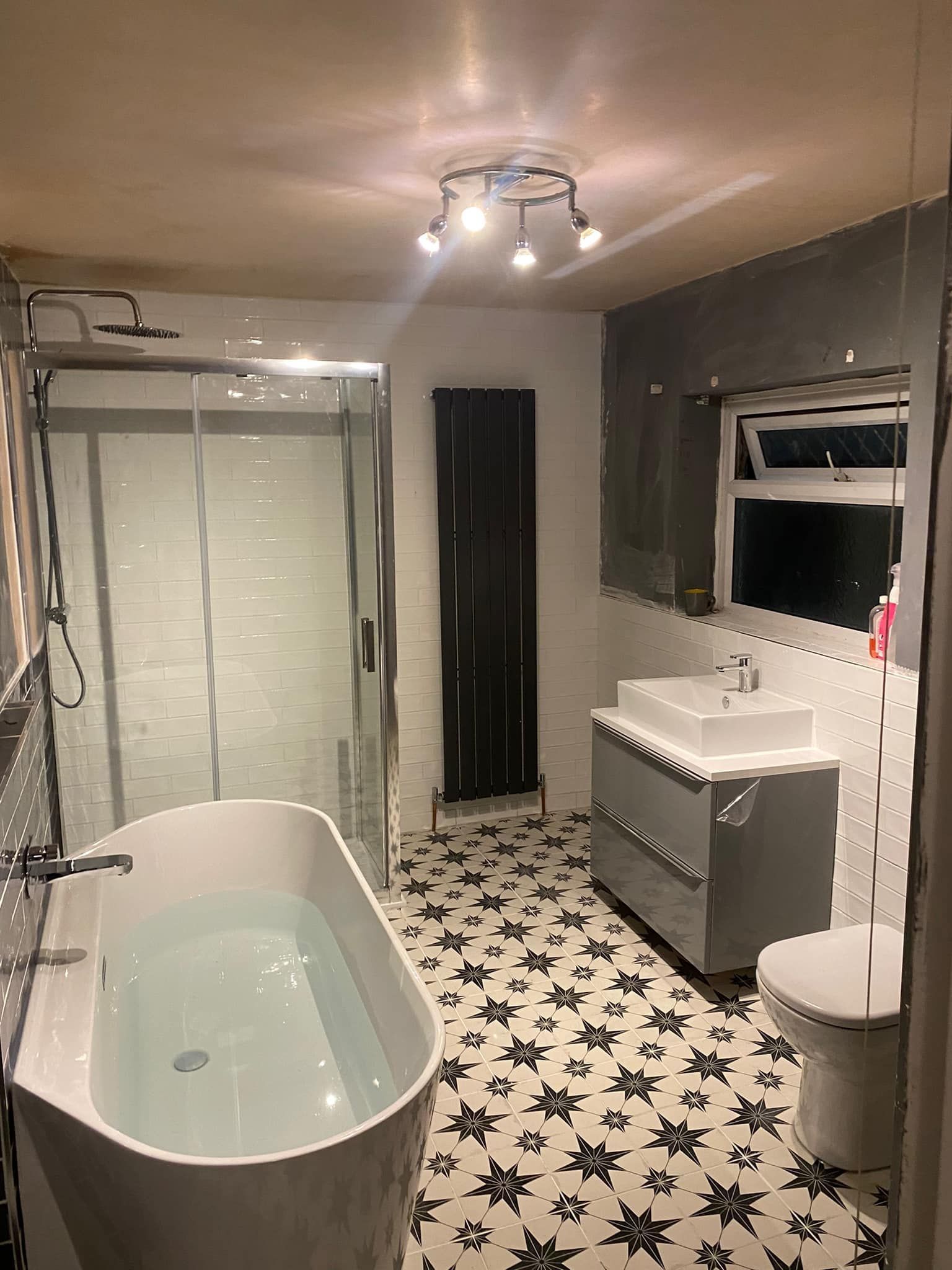 Modern bathroom with a bathtub, shower, sink, and patterned black and white floor tiles.