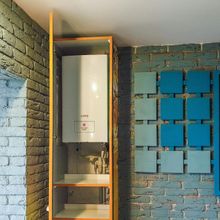 A gas boiler is housed in a wood cabinet mounted on a blue brick wall. Square blue tiles are adjacent.