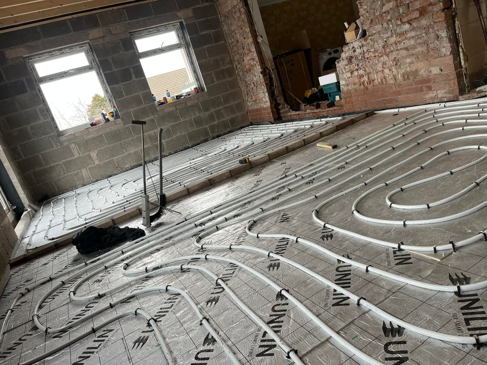 Interior room under construction, with underfloor heating pipes laid across the floor.
