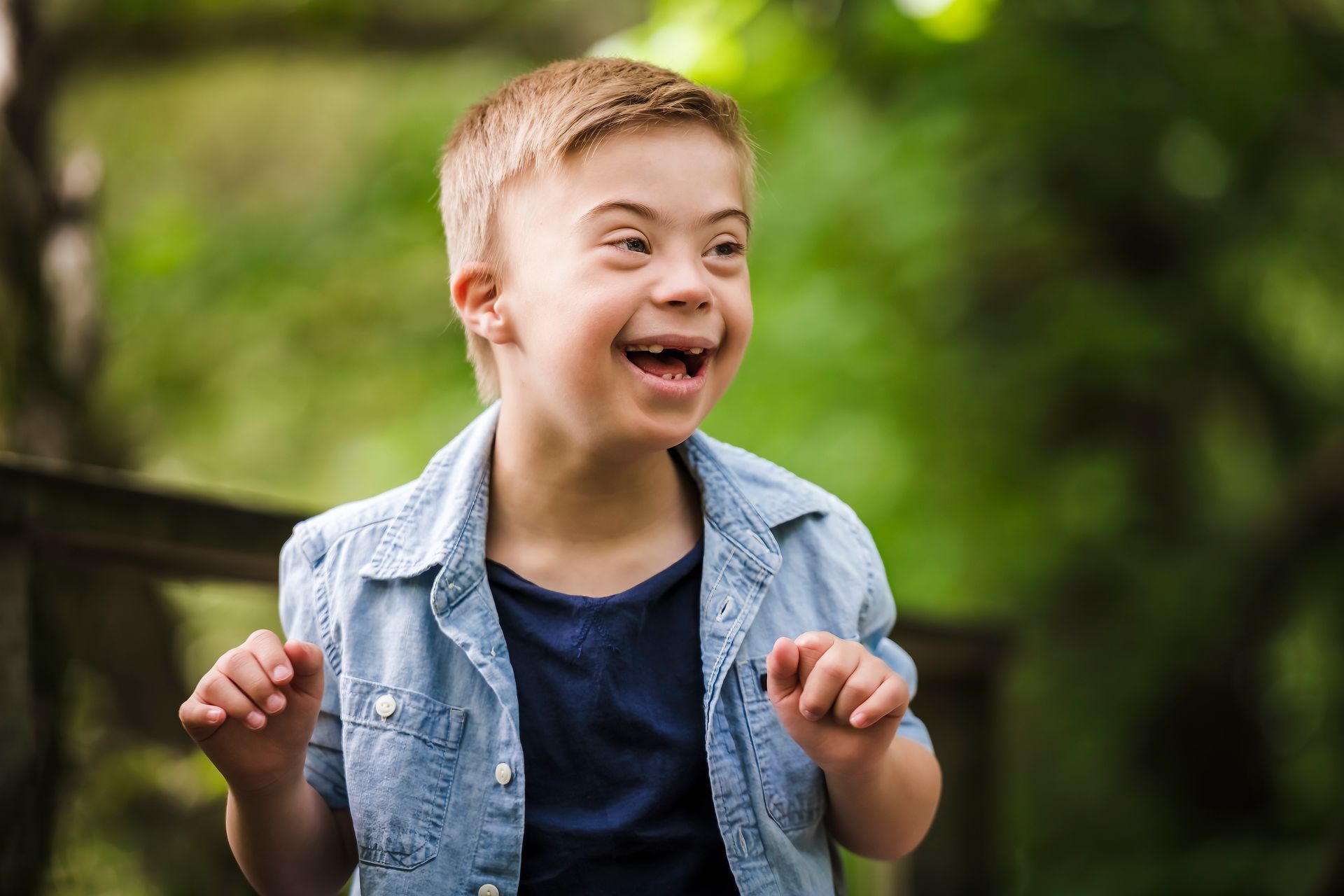 A young boy with down syndrome is smiling and making a funny face.