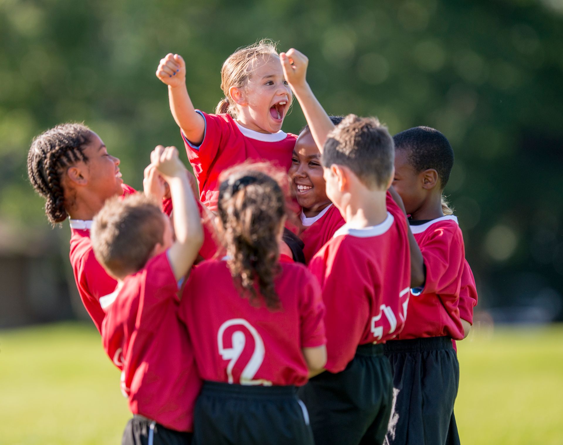 A group of young children are playing soccer on a field.