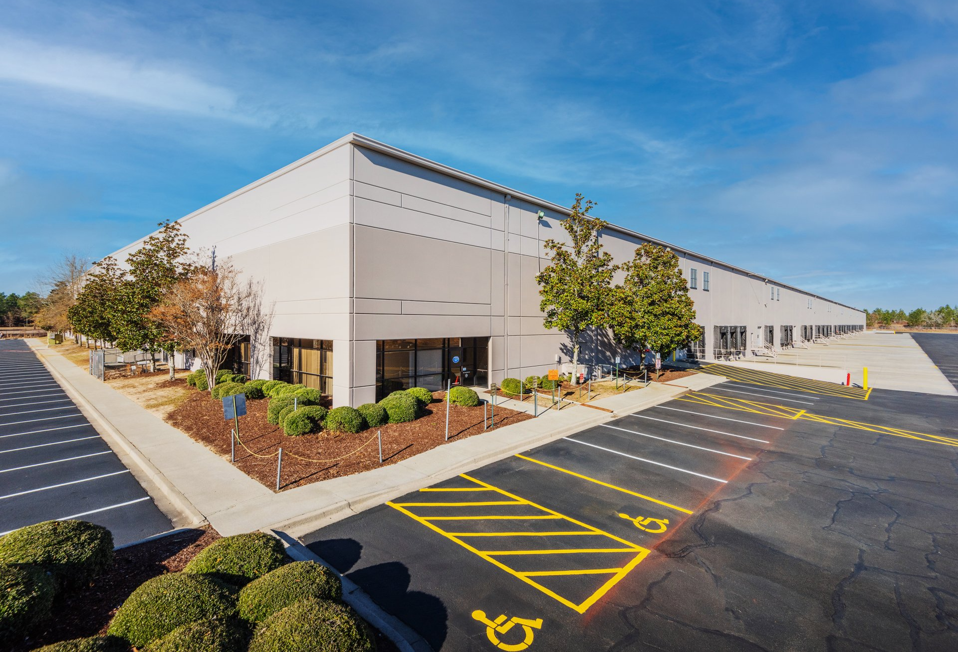 A large white building with a handicapped parking spot in front of it.