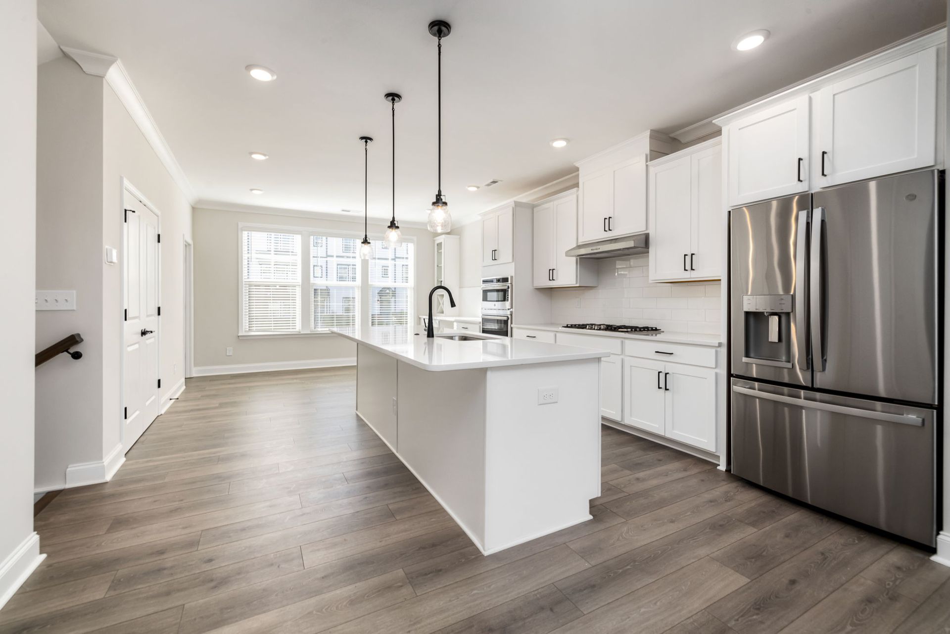 A kitchen with white cabinets and a stainless steel refrigerator.