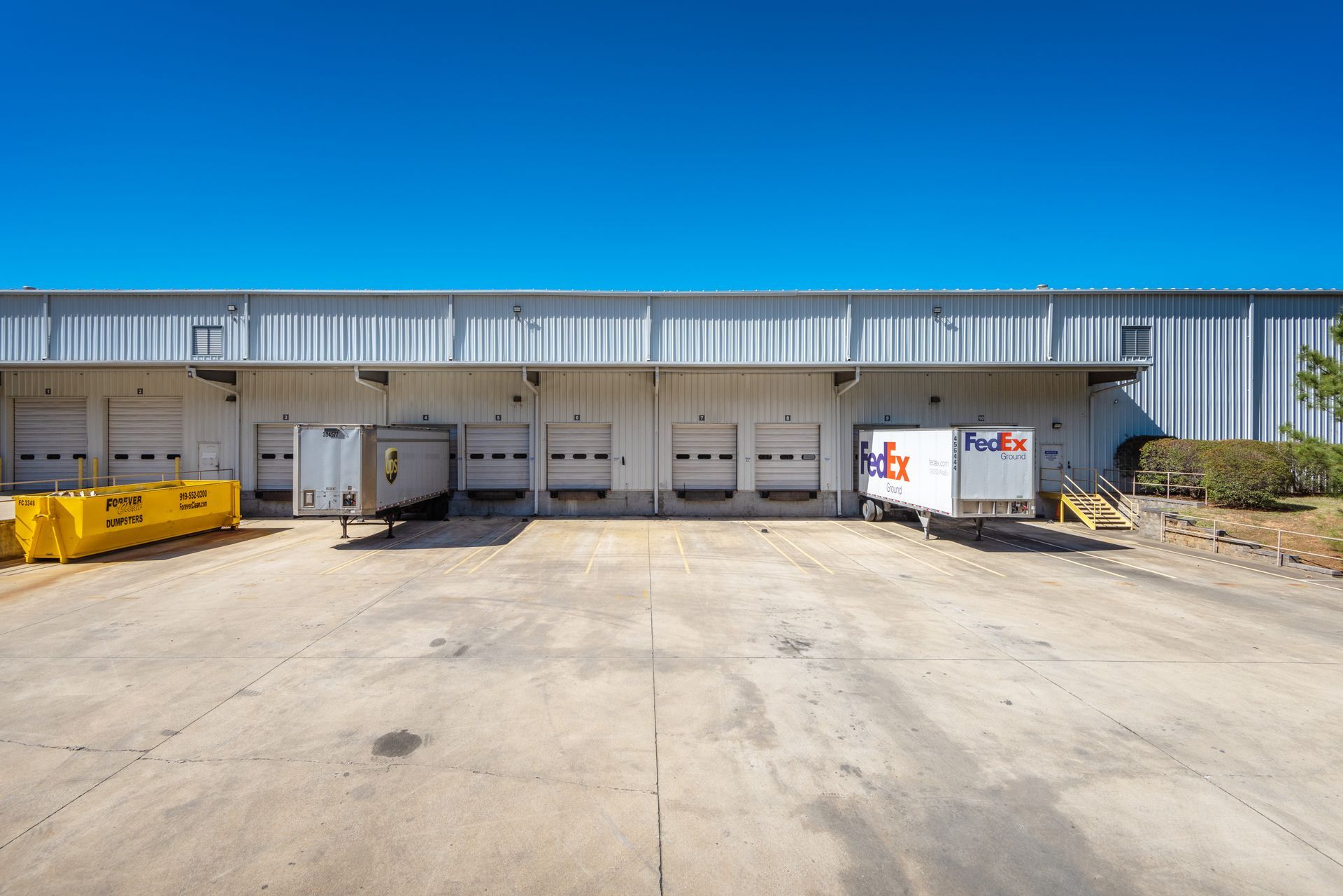 A fedex truck is parked in front of a large warehouse.