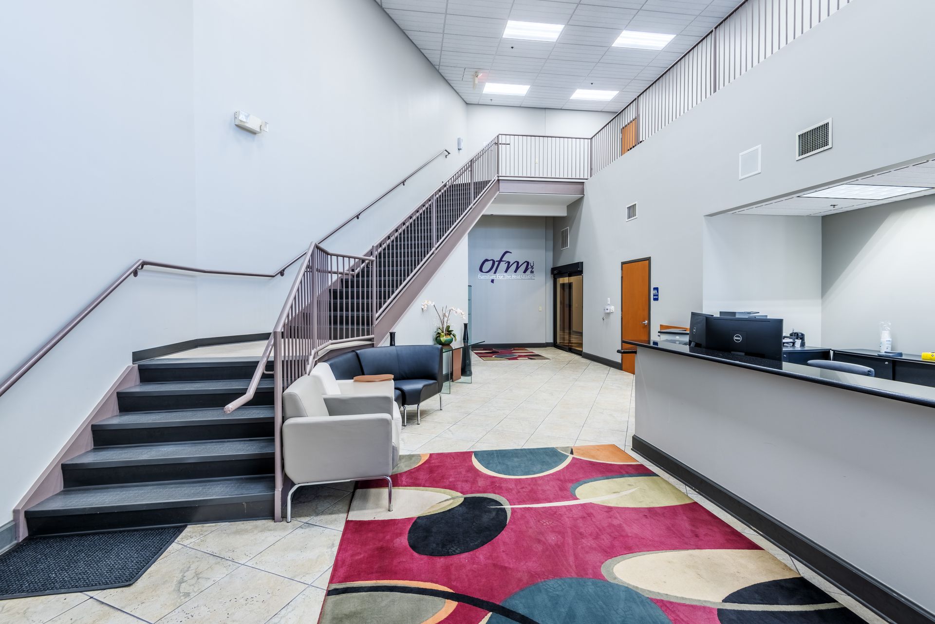 A lobby with stairs leading up to the second floor and a reception desk.