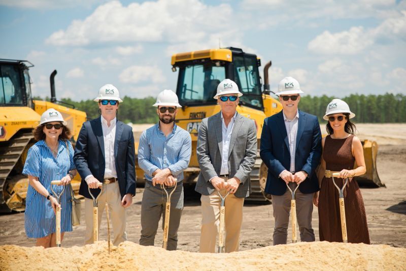 A group of people are standing next to each other on a construction site holding shovels.
