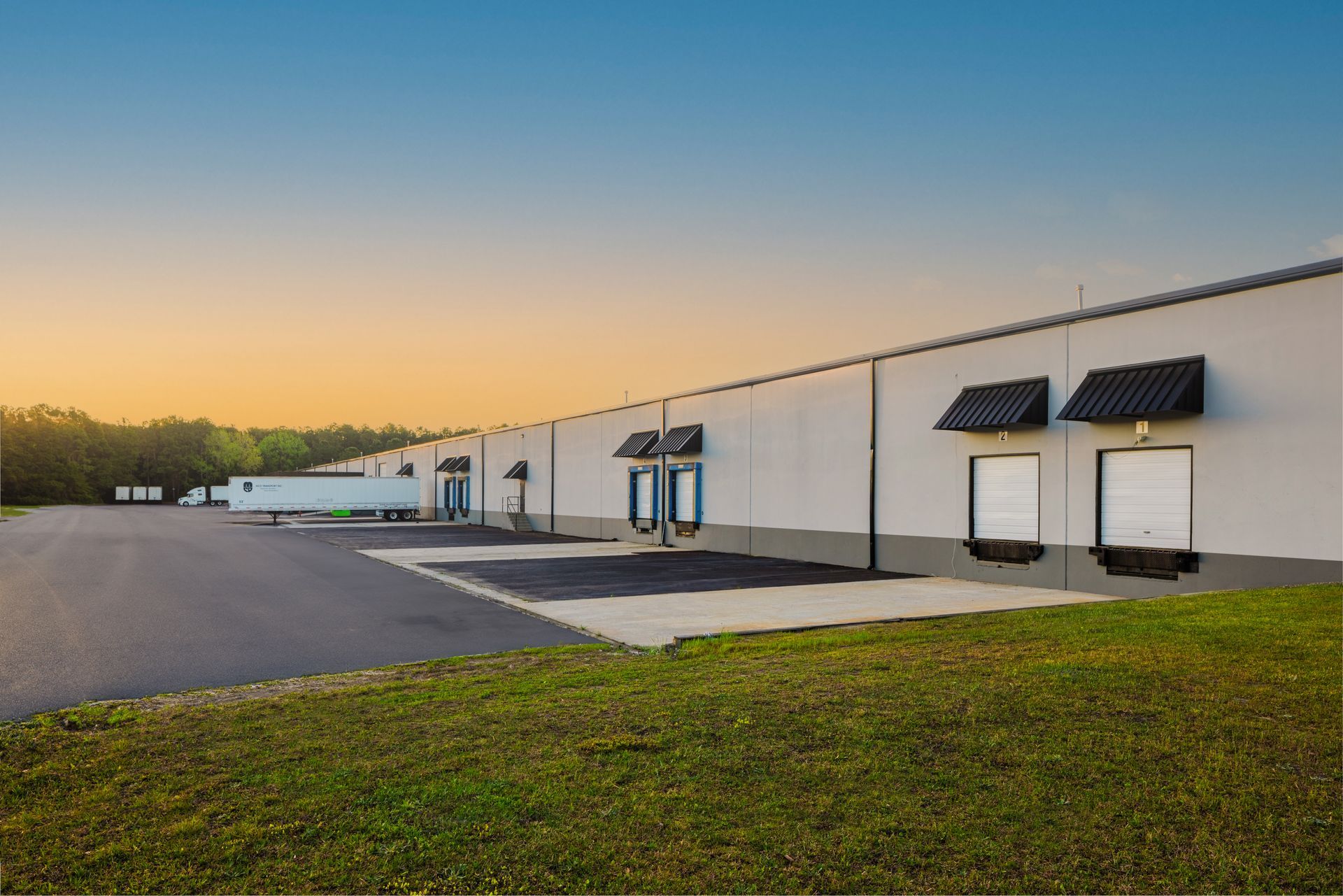 A large warehouse with a lot of trucks parked in front of it.