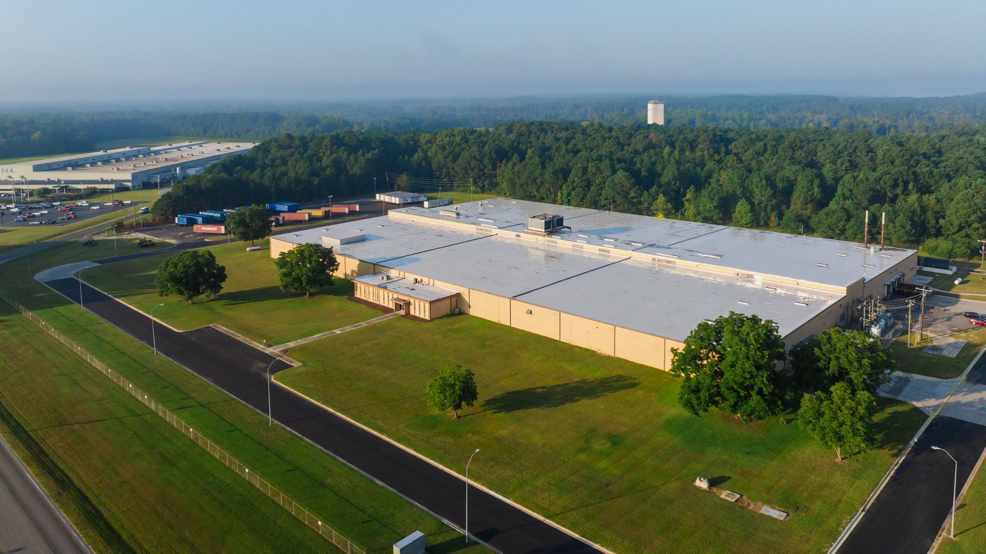 An aerial view of a large industrial building surrounded by trees and grass.