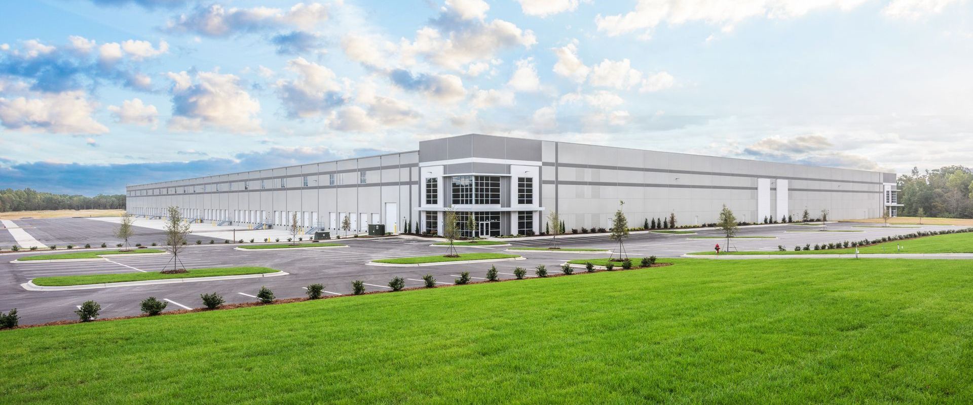 A large white building is sitting on top of a lush green field.