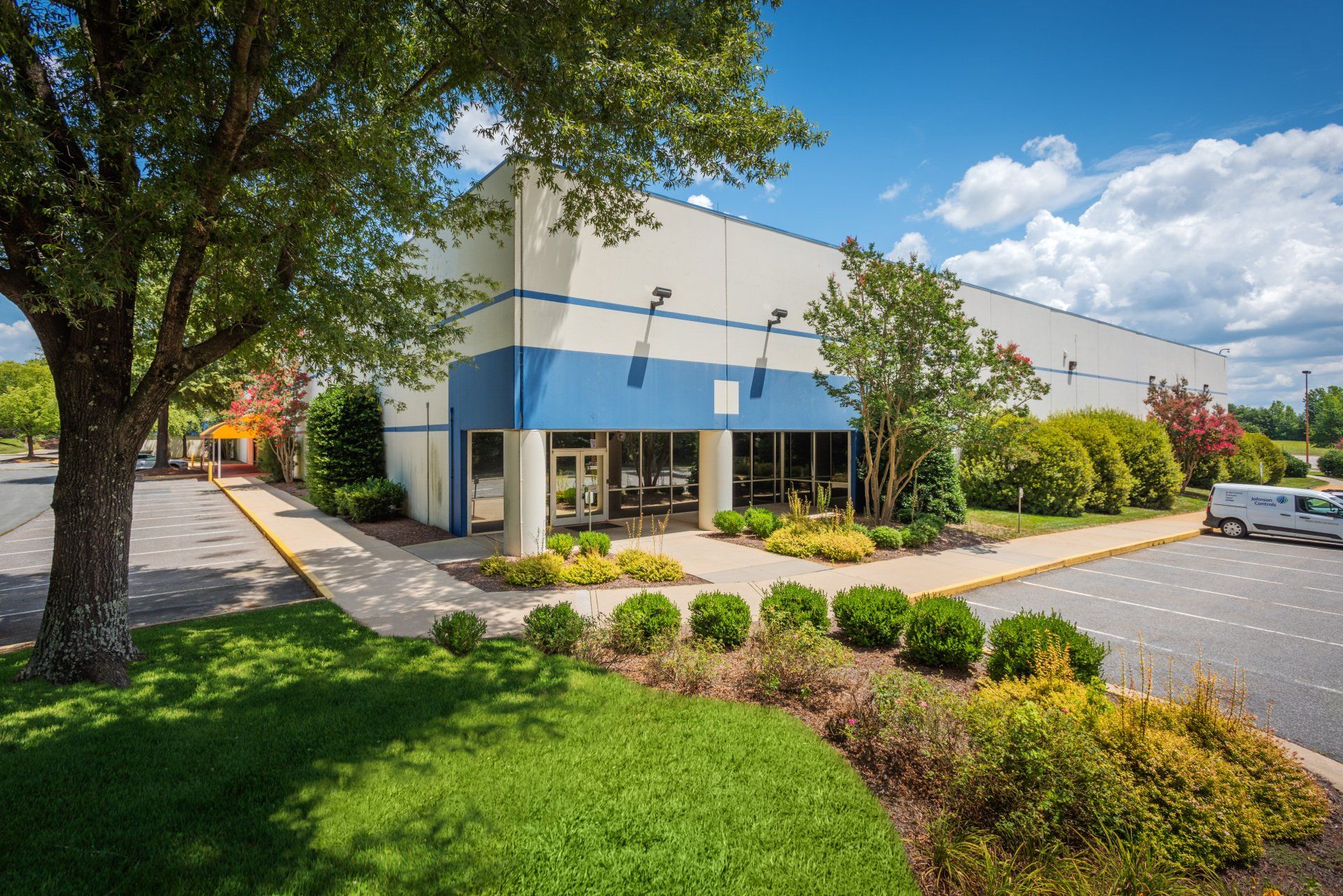 A large white and blue building with a parking lot in front of it.