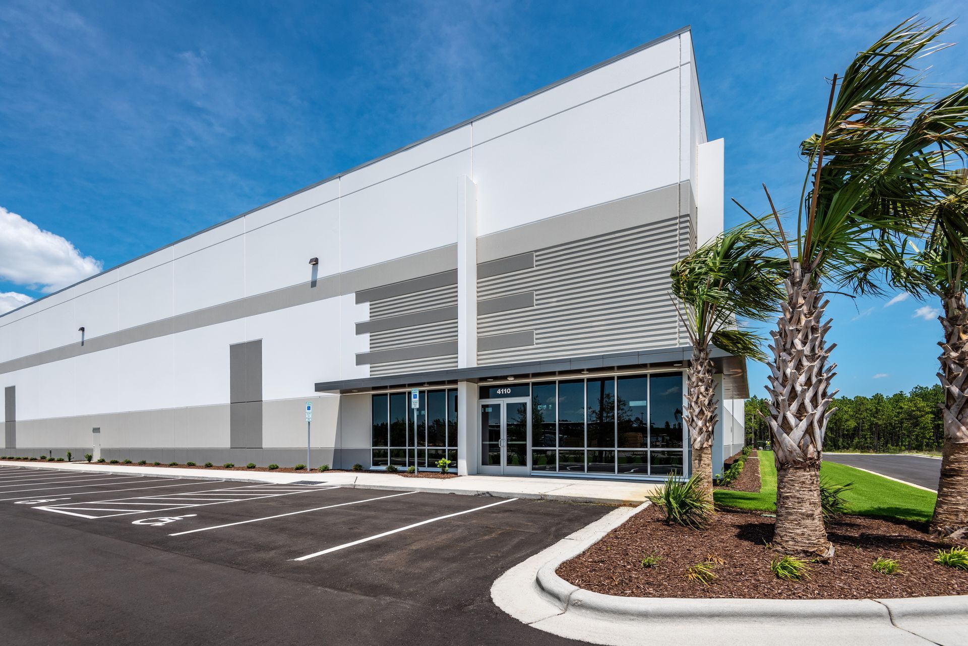 A large white building with a lot of windows and palm trees in front of it