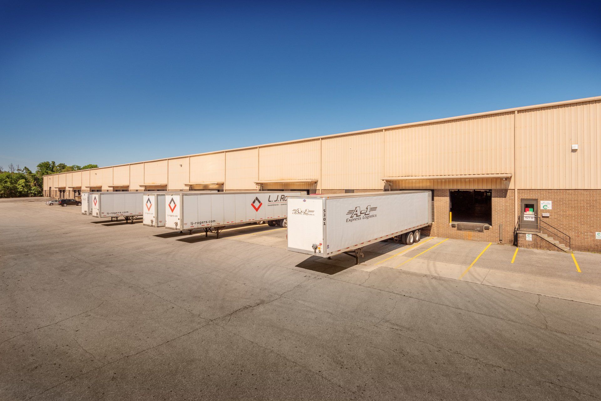 A row of semi trucks are parked in front of a building.