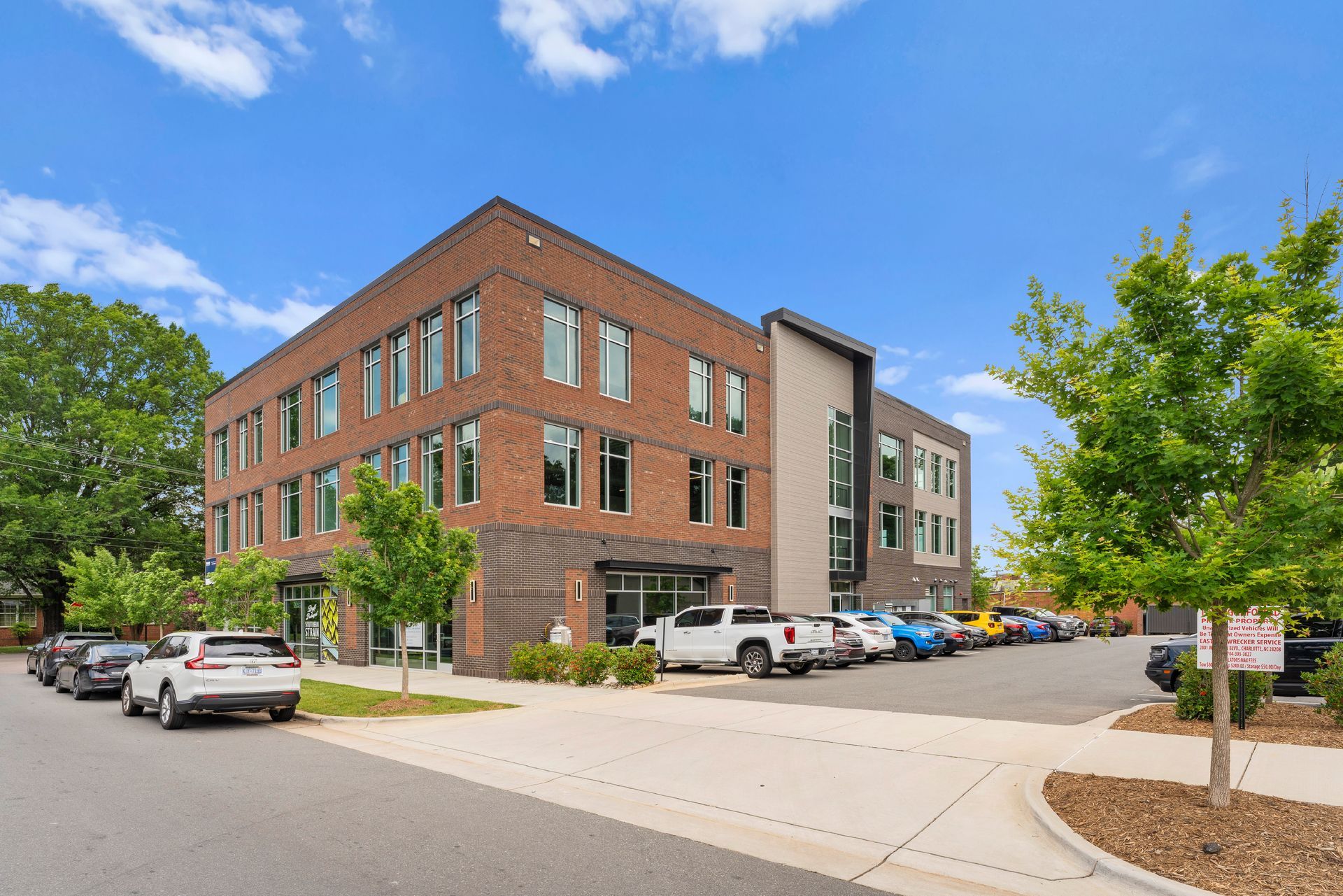 A large building with a lot of windows is sitting on the corner of a street.