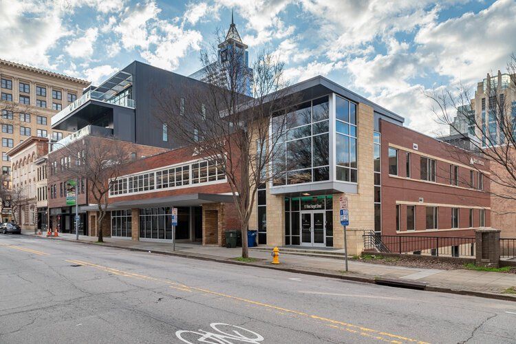 A large brick building with a lot of windows is on the side of a city street.
