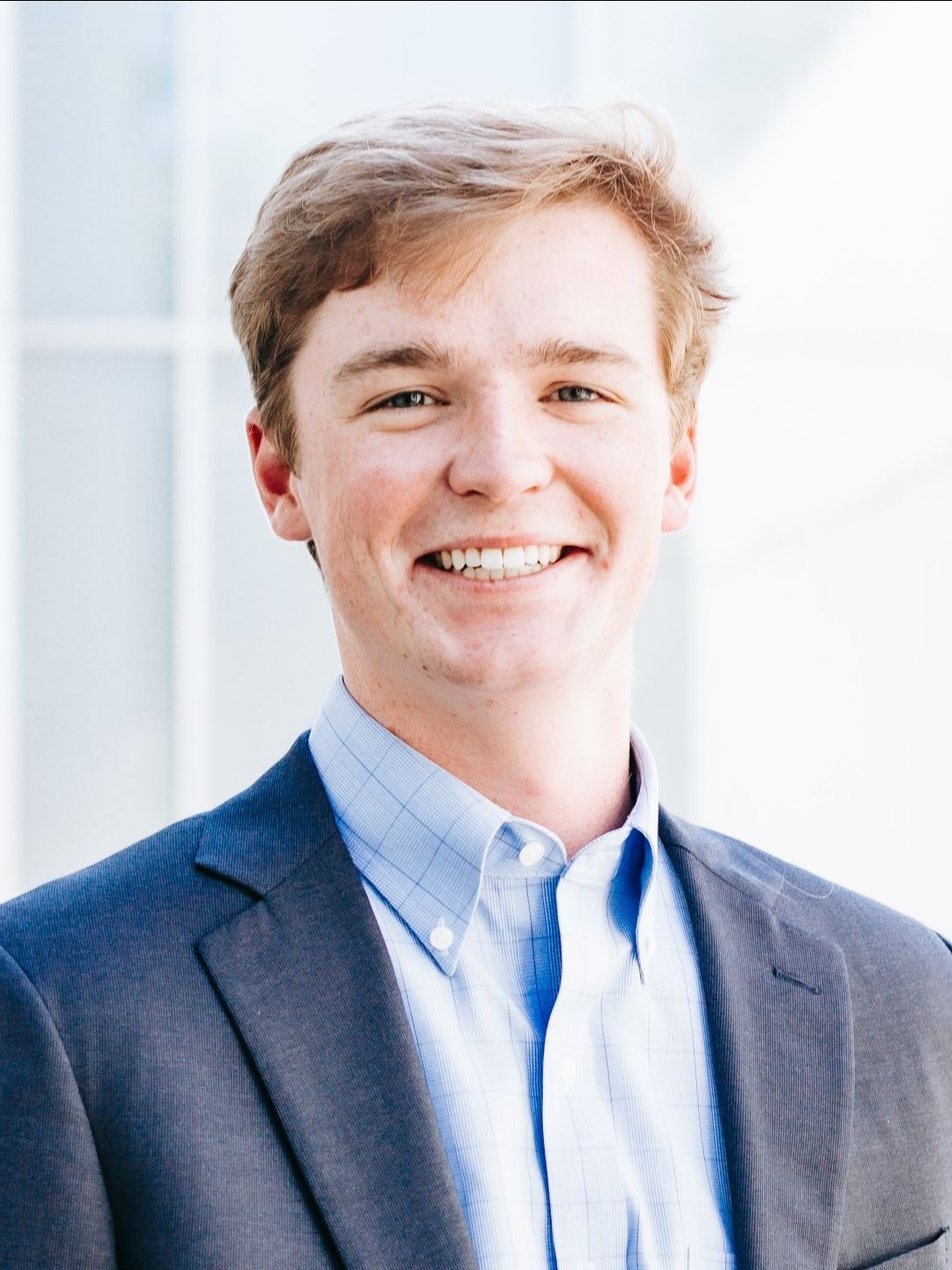 A young man in a suit and blue shirt is smiling for the camera.