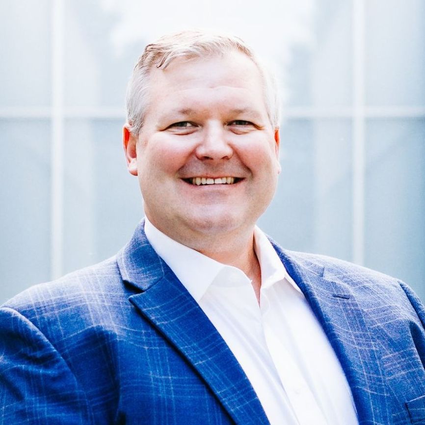 A man in a blue suit and white shirt is smiling for the camera.