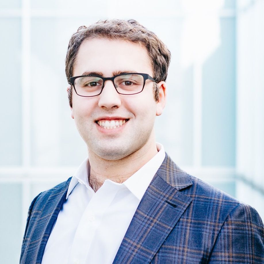 A man wearing glasses and a suit is smiling for the camera.