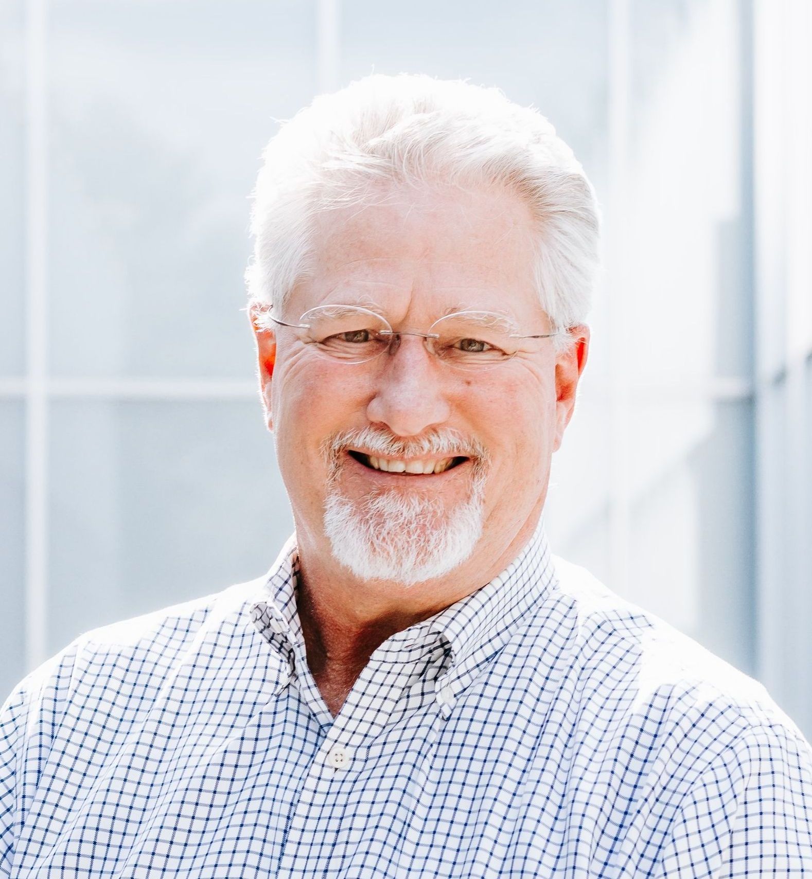 A man with glasses and a beard is smiling for the camera.
